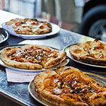 Meat lover's, mushroom and German Zwiebelkuchen pizzas hot out of the  oven