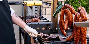 Magnolia MeatUp&trade; chefs prepare cuts of grilled, smoked, and sliced meat served throughout the club.